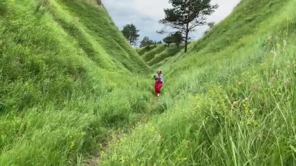 Kvinna promenader med en bukett blommor på de gröna kullarna — Stockvideo