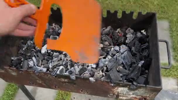 Un homme souffle des charbons dans un barbecue — Video