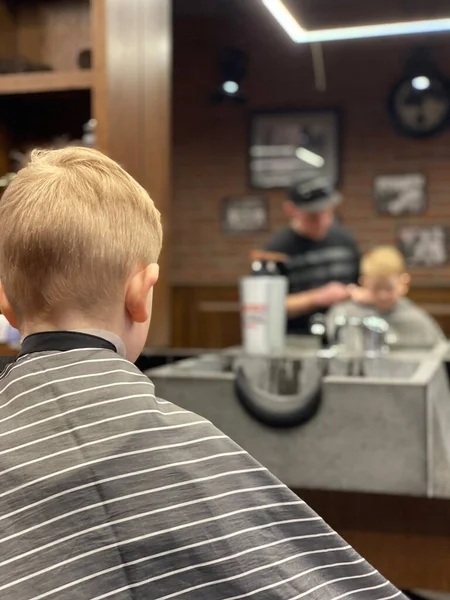 Master cuts a little boys hair in a barbershop — Stock Photo, Image