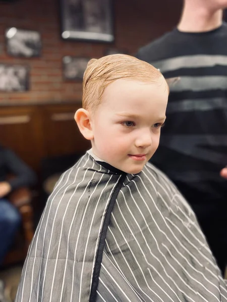 マスターは小さな男の子の髪を切ります理髪店で — ストック写真