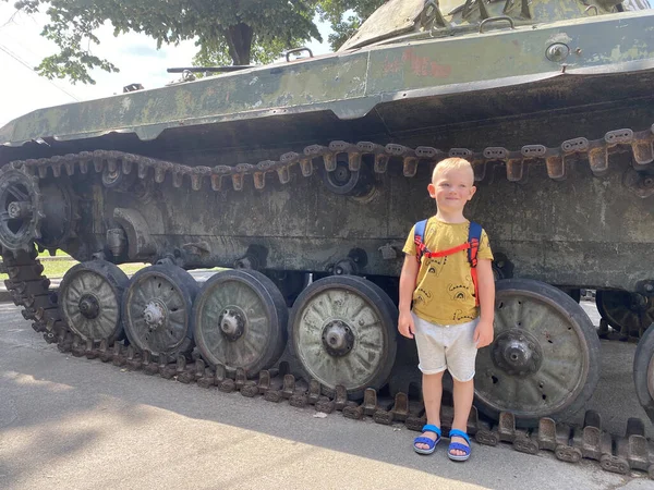 Çocuk Ukrayna, Kyiv 'deki Zafer Parkı' nda bir tankın önünde duruyor.