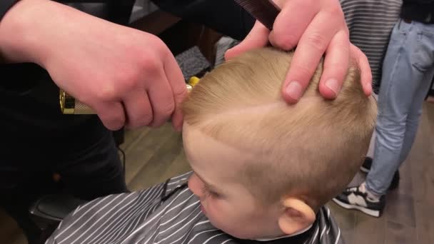 Mistr stříhá malé kluky vlasy v holičství — Stock video