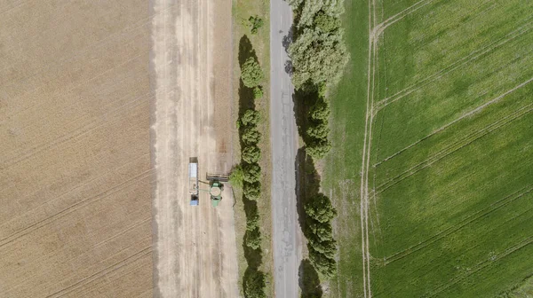 Luftaufnahme mit Erntemaschine, die Erntegut in einen LKW-Anhänger kippt — Stockfoto