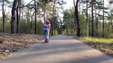 Modern mutlu kadın çam ormanında scooter sürüyor. 