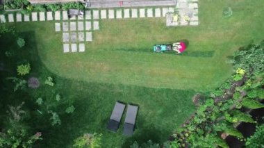 4k video footage of a man mowing the lawn. Aerial view.