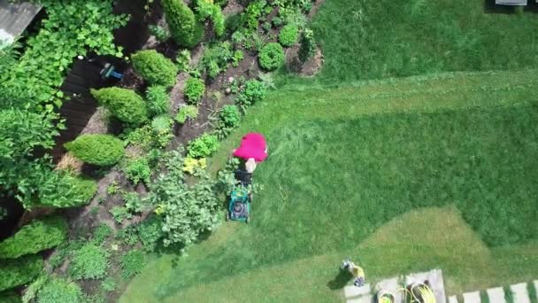 4k video footage of a man mowing the lawn. Aerial view. — стоковое видео