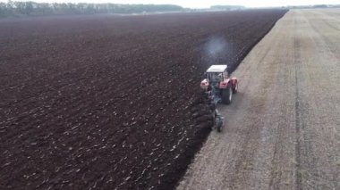 Tarladaki tarımsal kırmızı küçük traktör saban sürüyor.