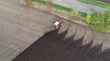 Tarladaki tarımsal kırmızı küçük traktör saban sürüyor.