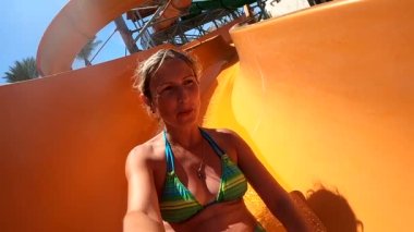 Young woman having fun going down the water slides in the water park