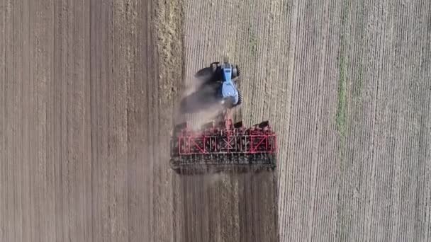 Zemědělský traktor na poli nadýmá zemi. Letecký pohled 4k video — Stock video