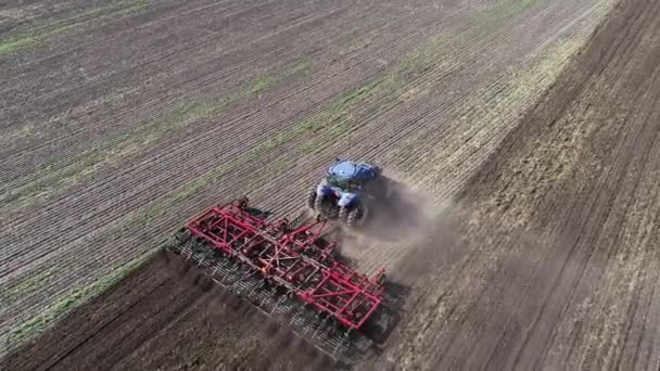 Agricultural tractor in the field fluff the earth. Aerial view 4k video — Stockvideo