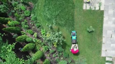 4k video footage of a man mowing the lawn. Aerial view.