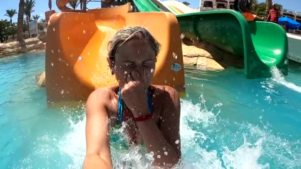 Young woman having fun going down the water slides in the water park — Stockvideo
