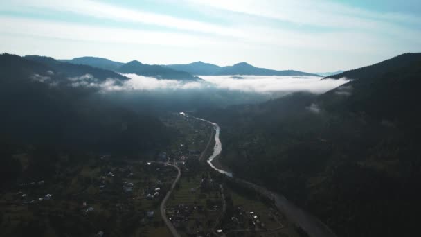 İnsansız hava aracı alçak bulutlu dağlık bir bölgedeki bir köyün üzerinde uçuyor. 4k video görüntüleri, Karpatlar, Ukrayna — Stok video