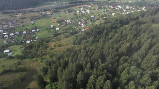 Drona zboară deasupra unui sat într-o zonă muntoasă cu nori joși în zonele joase. 4k imagini video, Carpați, Ucraina — Videoclip de stoc