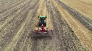 Agricultural tractor in the field fluff the earth. Aerial view 4k video