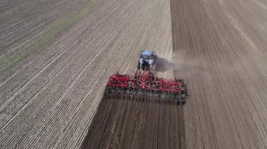 Agricultural tractor in the field fluff the earth. Aerial view 4k video