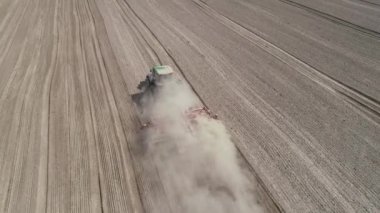 Tarlada tarla süren büyük yeşil traktör. Tarlada tarla sürme sistemi, yeni ekin ekimi için toprağı hazırlama, tarım konsepti, üst görünüm 4k video