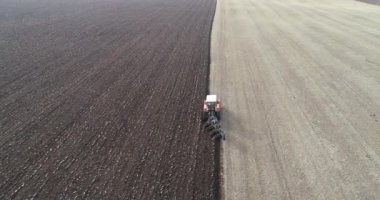 Agricultural red small tractor in the field plowing. System plowing ground on cultivated farm field, preparing soil for planting new crop, agriculture concept, top view