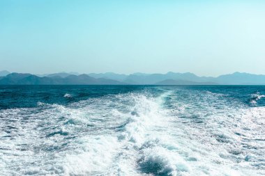 Arka planında dağlık bir kıyı bulunan mavi denizde yüksek hızlı bir gemiden görüntü. Yunanistan adalarını dolaş. Türk kıyıları