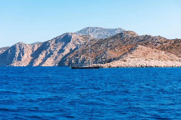 Yunanistan 'dan geçen bir gemiden adanın manzarası. Yat kayalık bir ada denizinin arka planında yüzüyor..