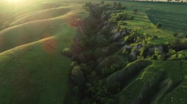 Baharın başında yemyeşil tepeler, bir vadi ve yeşil bir tarla ile güzel bir manzaranın 4k kalitesinde hava manzarası