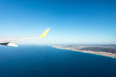 Kalkış sırasında uçak penceresinden denize bakan arka planda Rodos adası, Yunanistan