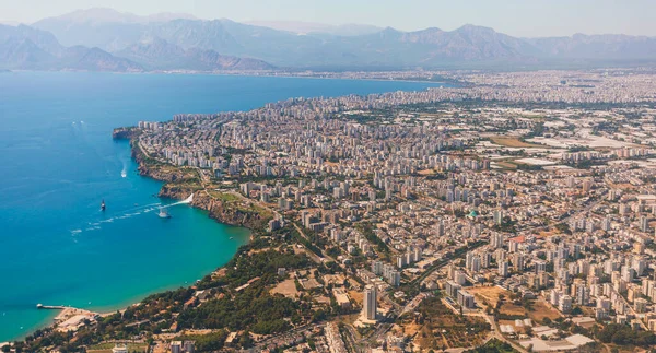 The view from the airplane window on the coast of Antalya with many houses, hotels, etc. with beautiful Taurus Mountains on the horizon, Turkey