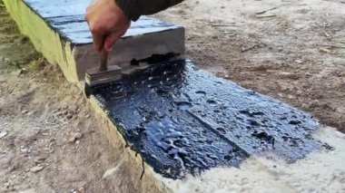İnşaatçı daha fazla duvar döşemesi için beton temelin tepesine devasa bir astar uygular. 4K video ağır çekim. Temel su geçirmez inşaat çalışmaları