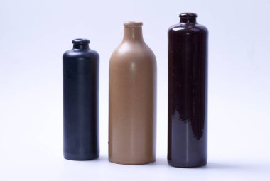 Farklı boylarda ve renklerde üç kil şişesi..