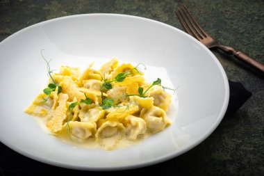 Ördekli Tortellini, beyaz tabakta kızarmış ekmek ve peynir sosu.