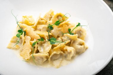 Beyaz tabakta ördek, kızarmış ekmek ve peynir soslu Tortellini.