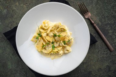 Ördekli Tortellini, beyaz tabakta kızarmış ekmek ve peynir sosu.