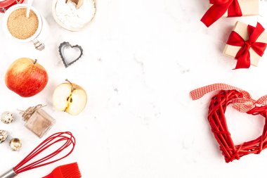 A frame with baking ingredients for Valentines Day or Birthday, a culinary background with pastries - whisk for whipping, cookie molds, apples, sugar, flour. White background, top view