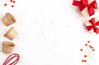 Beyaz arka planda ev yapımı için çerçeve. Kağıt kek kalıpları. Sevgililer Günü için kırmızı kurdeleli kutular. Uzayı kopyala Üst görünüm