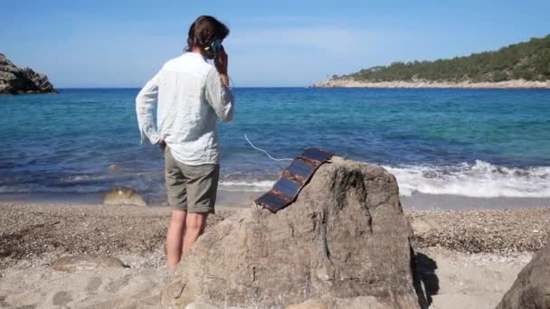 Kız Turist Telefonda Konuşuyor Deniz Kıyısındaki Güneş Panelinden Şarj Ediyor — Stok video