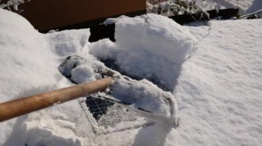 Evin çatısındaki güneş panellerinden kürekle kar ve buz temizliyorum. .
