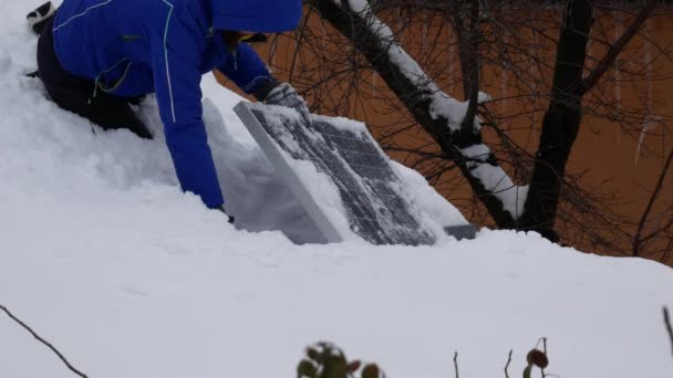 Seorang Gadis Sedang Menggali Panel Surya Dari Salju Atap Rumahnya — Stok Video
