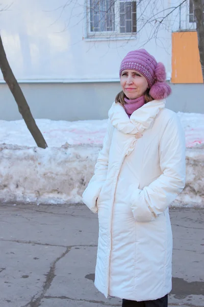 Una mujer con un abrigo blanco caminando por la ciudad — Foto de Stock