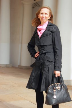 siyah pelerin ve siyah bir çanta içinde bir kadın portresi