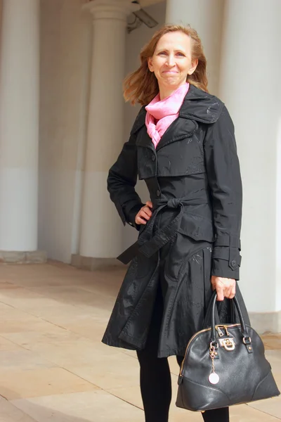 Portrait of a woman in a black cloak and a black bag — Stock Photo, Image