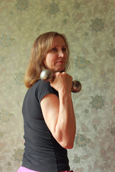 A woman with a dumbbell has been charging — Stock Photo, Image