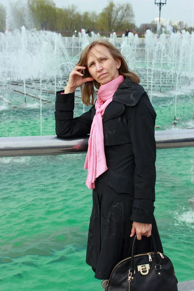 Eine Frau steht neben einem Brunnen — Stockfoto