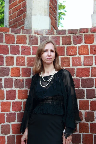 Traurige Frau steht nahe Ziegelmauer — Stockfoto
