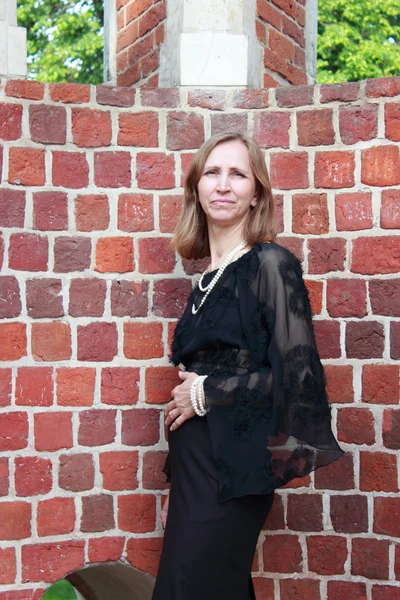 A woman stands near the brick wall — Stock Photo, Image