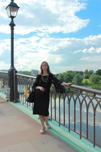Kobieta w czarnej sukni stojącej na moście — Zdjęcie stockowe