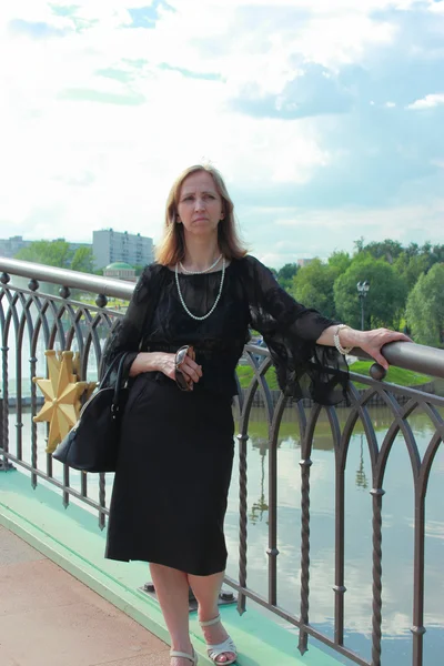 Une femme en robe noire debout sur le pont — Photo