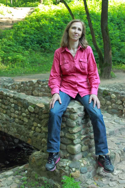 Une femme assise sur un pont de pierre parapet — Photo