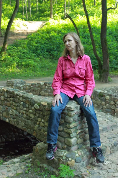 Een vrouw zitten op een stenen brug borstwering — Stockfoto