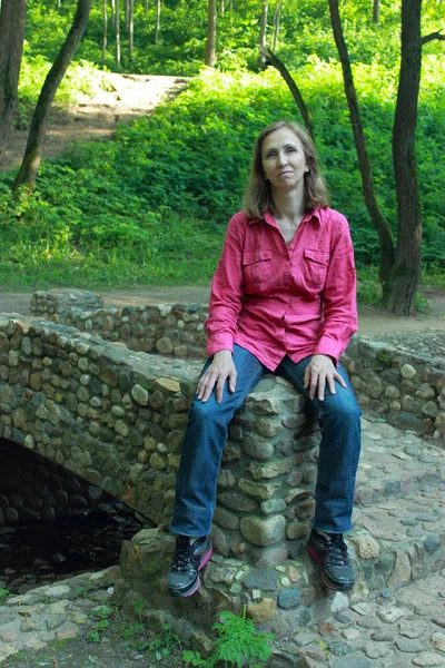 Une femme assise sur un pont de pierre parapet — Photo